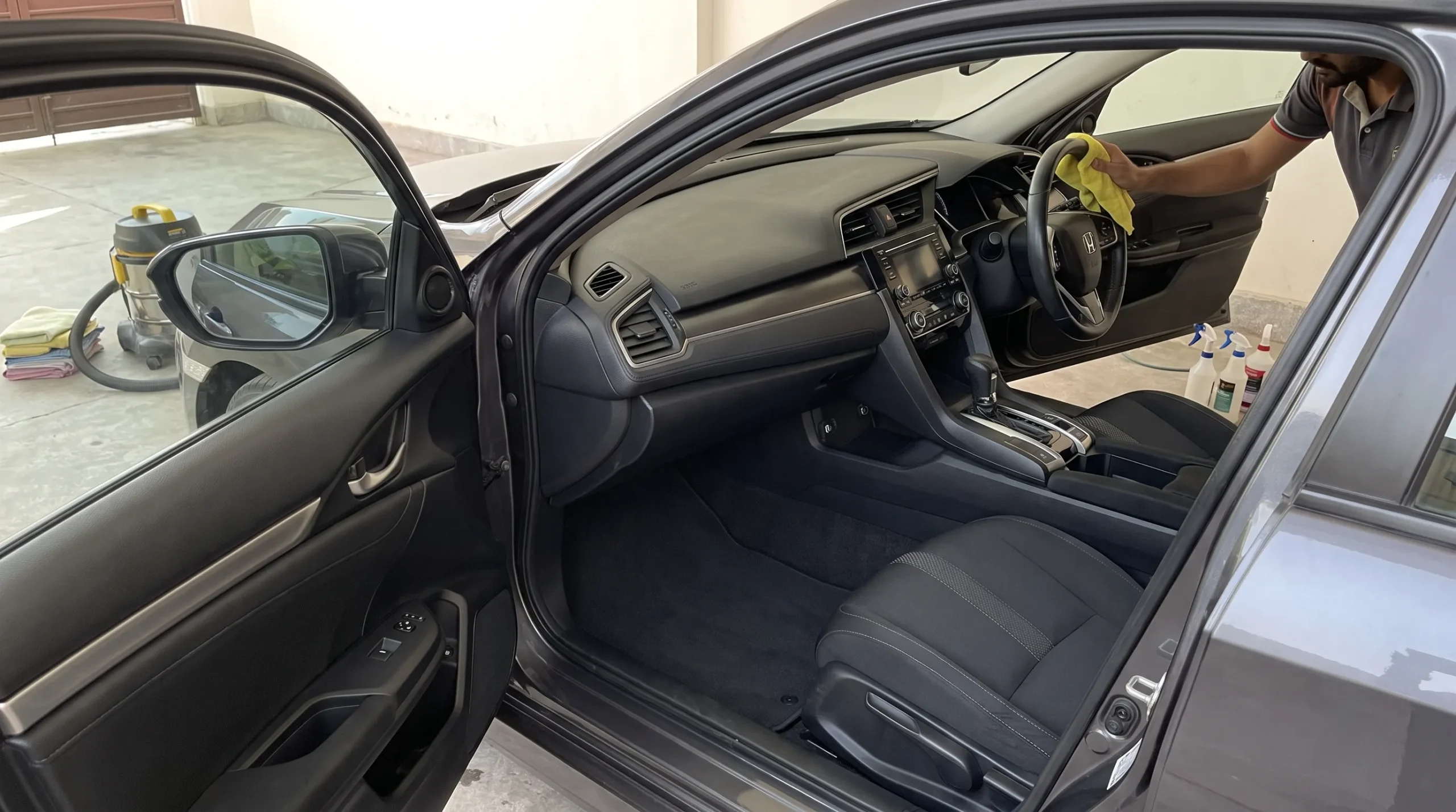 Car interior detailing at home with dashboard and seats being cleaned